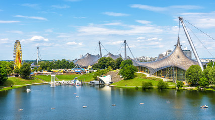 Wall Mural - Munich Olympiapark in summer, Germany. It is the Olympic Park, landmark of Munich. Scenic view of former sport area. Panorama of the green Munich district with lake. Beautiful skyline of Munich city.