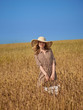 © drouk - A blonde in a wheat field walks with a wicker basket of apples in a lime hat and a vertical striped dress.