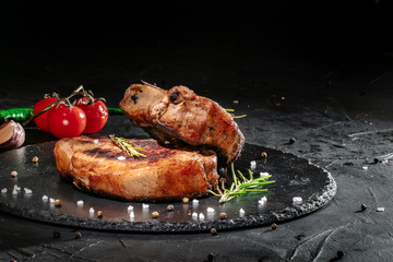 Grilled steak with herbs, spices and cherry tomatoes on dark background