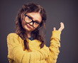 © nastia1983 - Thinking angry kid girl gesticulating the hand in eyeglasses on grey studio background. Closeup toned color portrait