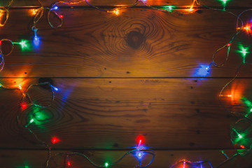 Christmas decorative lights. Christmas garland lights on wood. Colorful Xmas light bulbs on rustic brown plank