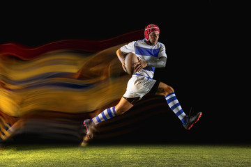 Ready for winning. One caucasian man playing rugby on the stadium in mixed light. Fit young male player in motion or action during sport game. Concept of movement, sport, healthy lifestyle.