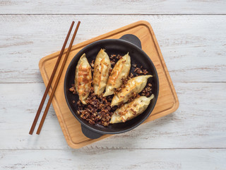 Fried dumplings Gyoza in a frying pan, soy sauce, and chopsticks on a white wooden background, top view. 