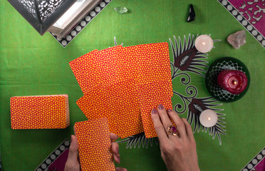 Divination by tarot cards on a background of a green tablecloth with burning candles.