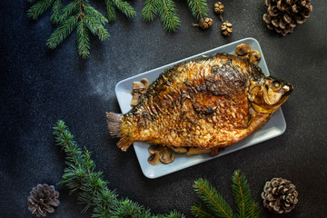 Christmas whole Carp baked with mushrooms. Served on a dark background. Traditional Christmas Eve meal. Top view. Space for text