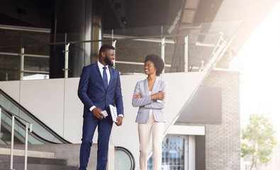 Businessman and businesswoman discussing work while walking outdoors