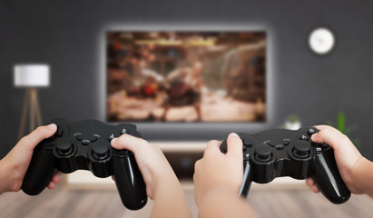 Wall Mural - Gaming in living room concept. Two boys holding gamepad and play console game on TV.