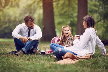 Wall Mural - Young Family after work and school sitting and resting at park..