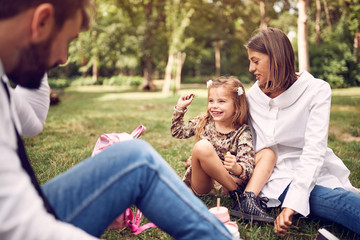 Wall Mural - daughter with their mother and father sitting and resting at park..