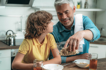 Wall Mural - Happy son with father heaving breakfast at kitchen