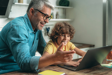 Canvas Print - Father and son looking at laptop display