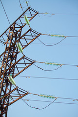 Bottom view on high voltage power lines against the blue cloudless sky