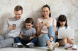 © fizkes - Happy technology addicted parents and kids use devices at home