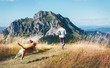 © Soloviova Liudmyla - Female running by the mounting range path with her beagle dog back view. Canicross running healthy lifestyle concept image.
