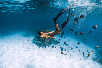 Wall Mural - Woman freediver dive with fins over sandy sea with fishes in Hawaii