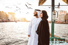 Happy Couple Spending Time In Dubai. Man And Woman Wearing Traditional Clothes Taking A Cruise On The River
