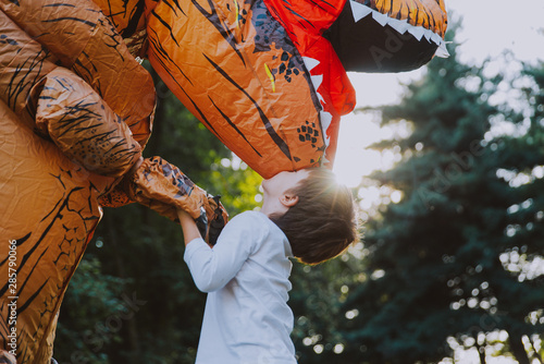 Father and son playing at the park, with a dinosaur costume, having fun with the Fototapeta