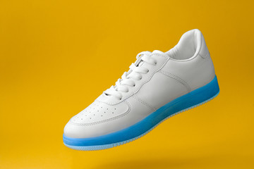 trendy white sneakers with blue sole  isolated on yellow background