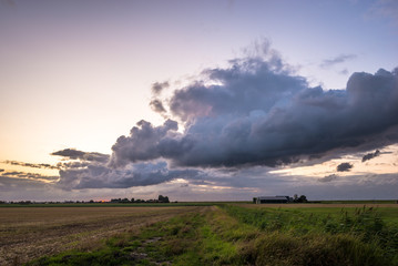 Wall Mural - beautiful clouds over the flat, wide open dutch landscape at dusk