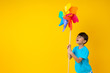 Portrait of funny young Asian Thai pretty girl holding and playing colorful turbine on yellow background