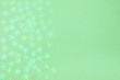 Holographic foil snowflakes confetti sparse on trendy neo mint colored background. Simple holiday concept. Winter festive backdrop. Design template. Copy space for text. Top view, flat lay.