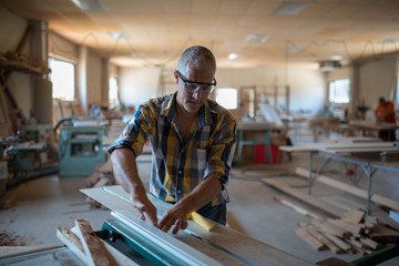 a carpenter processes a massive piece of wood