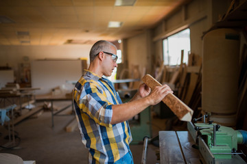 a carpenter measures a massive piece of wood