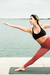 © Дарья Фомина - Asian young girl doing yoga outdoors on the pier by the lake.