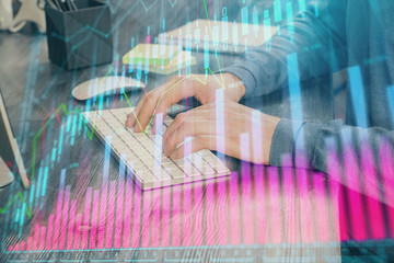 Stock graph with businessman typing on computer in office on background. Concept of analysis. Double exposure.