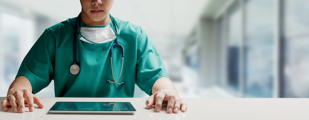 Wall Mural - Surgeon doctor sitting at table with tablet computer in hospital office. Medical healthcare staff and doctor service.