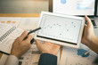 © wutzkoh - Business partnership coworkers analysis cost work progress and using a tablet to graph company financial budget report and planning for future in office room.