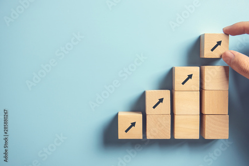 Fotografía Business concept growth success process, Close up Woman hand arranging wood block stacking as step stair on paper blue background, copy space