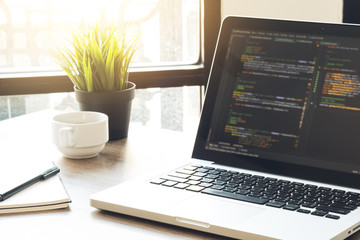 wood software developer or programmer office desk table with laptop with the software code on the sc