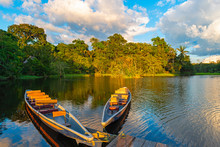 Two Traditional Wooden Canoes At Sunset In The Amazon River Basin With The Tropical Rainforest In The Background Inside The Yasuni National Park, Ecuador, South America.