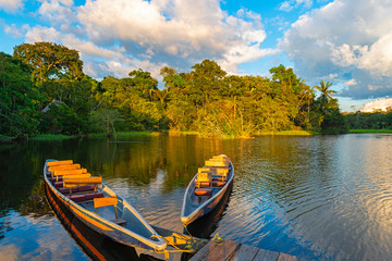 Wall Mural - Two traditional wooden canoes at sunset in the Amazon River Basin with the tropical rainforest in the background inside the Yasuni National Park, Ecuador, South America.
