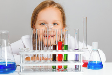 Little girl student looks at test tubes. A child is conducting a chemical experiment.