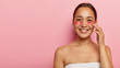 © wayhome.studio  - Cheerful korean female poses bare shoulders, has cosmetic patches on face, avoids problem of dark circles under eyes, touches fresh skin, stands against pink wall with empty space for your advert