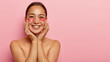 © wayhome.studio  - Portrait of cheerful korean woman smiles happily, applies cosmetic patches under eyes, touches cheeks gently, has healthy skin, cares about her beauty, poses shirtless against pink background