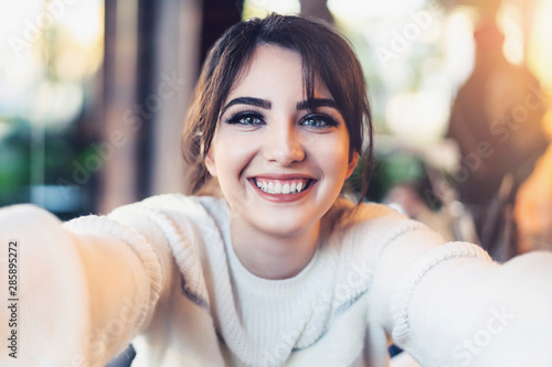 Fotomural Smiling girl taking selfie with her hands for social networks while sitting in cafe