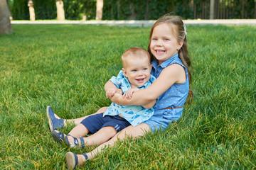 children sister with brother in the park on the grass