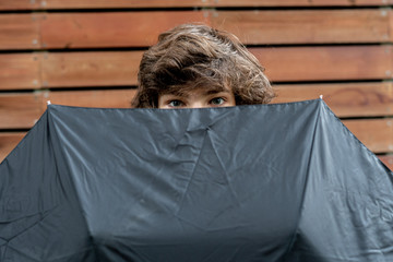 young teenager holding umbrella, protecting himself from problems