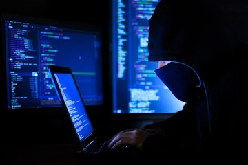 Wall Mural - man in hood and mask is hacking password, phishing. programmer developer is writing code malware sof