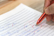 © NuPenDekDee - Concept of measurement and evaluation. Hand of teacher using red pen written grade A and circle on math exam paper on wood desk.
