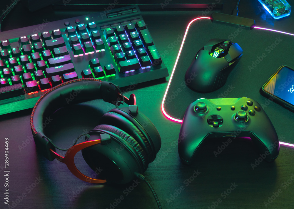 gamer work space concept, top view a gaming gear, mouse, keyboard, joystick, headset, mobile joystick, in ear headphone and mouse pad on black table background. - obrazy, fototapety, plakaty 