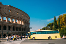 Rome, Italy. Colosseum. Yellow Bus Moving On Street Near Flavian Amphitheatre. Famous World UNESCO Landmark