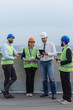 © VisionPro - Multiethnic group of workers engineers architects foreman analyzing the plan of construction site on the rooftop of modern building.