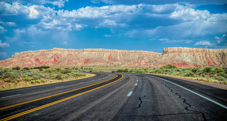 Canvas Print - Arid landscape of Arizona. The crumbling sandstone mountains and the highway	