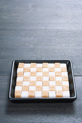 brown and white sugar nubs on black square plate, wood table