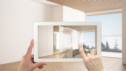 Augmented reality concept. Hand holding tablet with AR application used to simulate furniture and design products in empty interior with parquet floor, luxury bedroom with shower