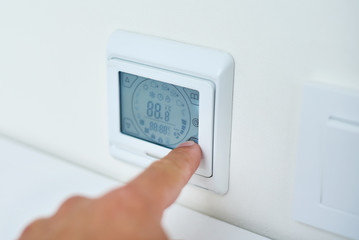 Men hand setting temperature on the underfloor heating control panel